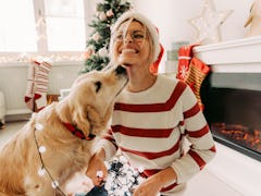 Photo of young woman and her dog enjoying together at home in a Christmas atmosphere with Christmas ...