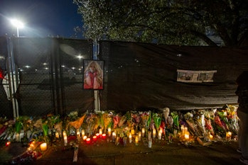The photo of a woman is left on the fence as candles are lit at a makeshift memorial on November 7, ...