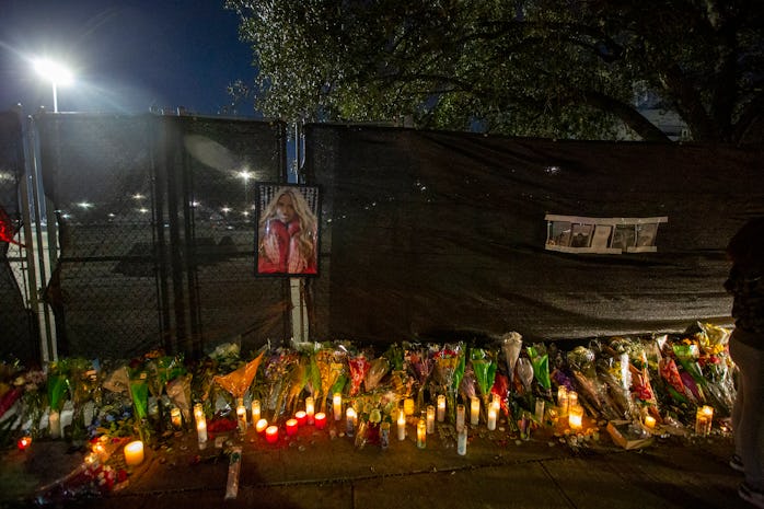 The photo of a woman is left on the fence as candles are lit at a makeshift memorial on November 7, ...