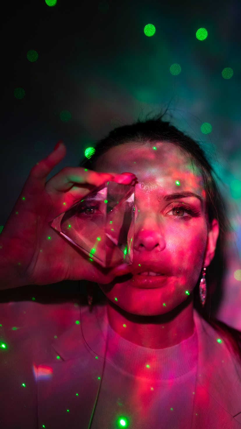 young woman holds a sphere up to her eye as she reflects on the best crystal for her zodiac sign
