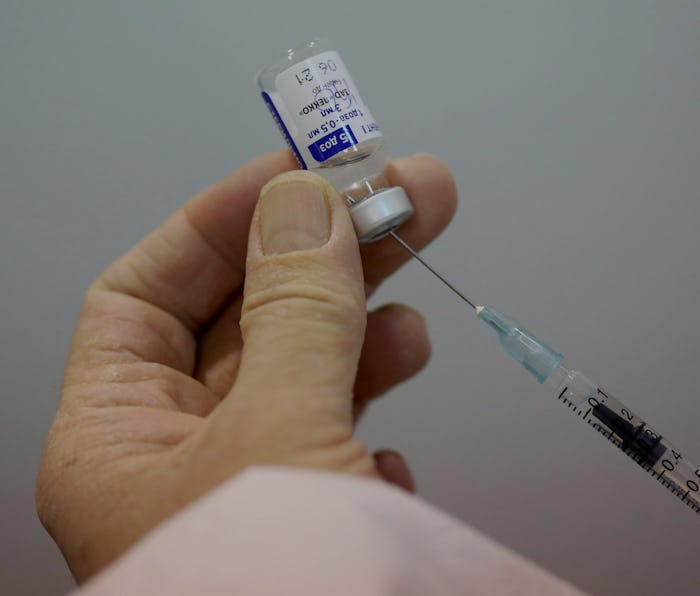 Close-up of hands filling a syringe with a COVID-19 vaccine.