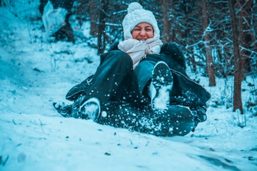 A happy woman slides down a hill in a snow tube.