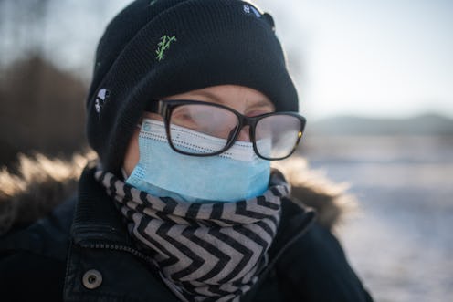 A person wears a winter coat, beanie, mask and glasses, with their glasses fogging up. There's a sim...