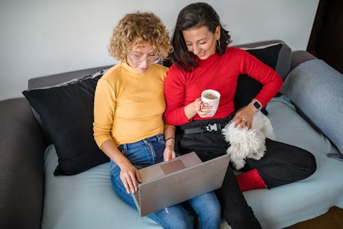 Two women sit on a couch and play Valentine's Day zoom games.