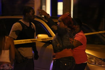 A Chicago Police officer at a late-night crime scene, talking to two women