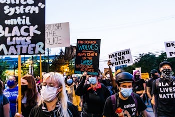 Protestors holding signs saying "Black Lives Matter," "Defund the Police" and other slogans