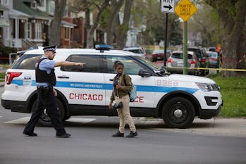 A Chicago Police officer pointing past a black woman in front of a police vehicle