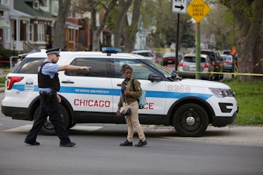 A Chicago Police officer pointing past a black woman in front of a police vehicle