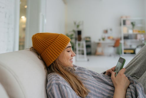 A woman wearing an orange beanie buys fake followers on Instagram.