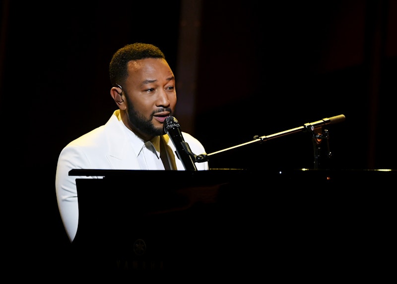 American singer John Legend playing a piano and singing during his concert