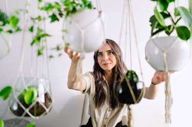 A young woman holds macrame plant hangings from TikTok.
