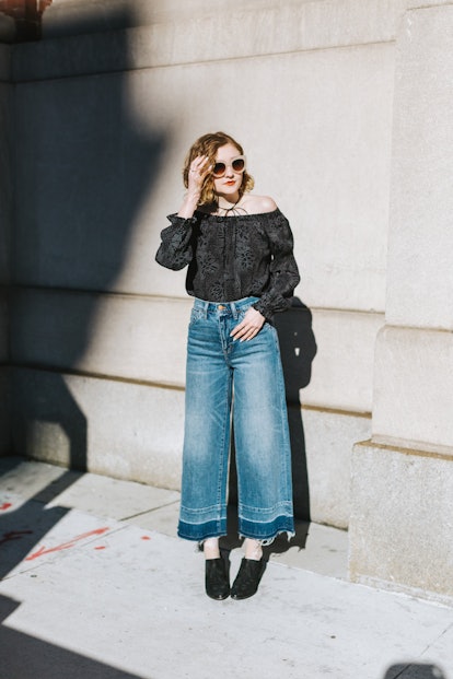 A young woman poses in a pair of flared jeans on a sunny day.