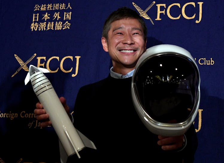 Yusaku Maezawa holding a model rocket and a space helmet.