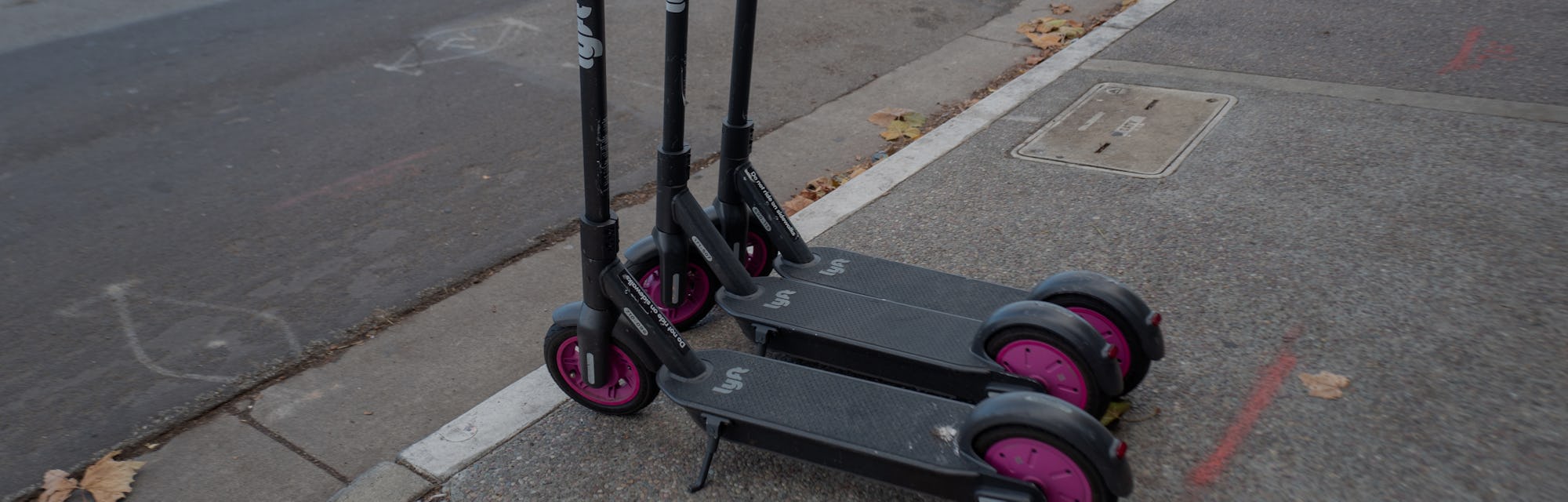 Two Lyft electric scooters parked on a sidewalk.