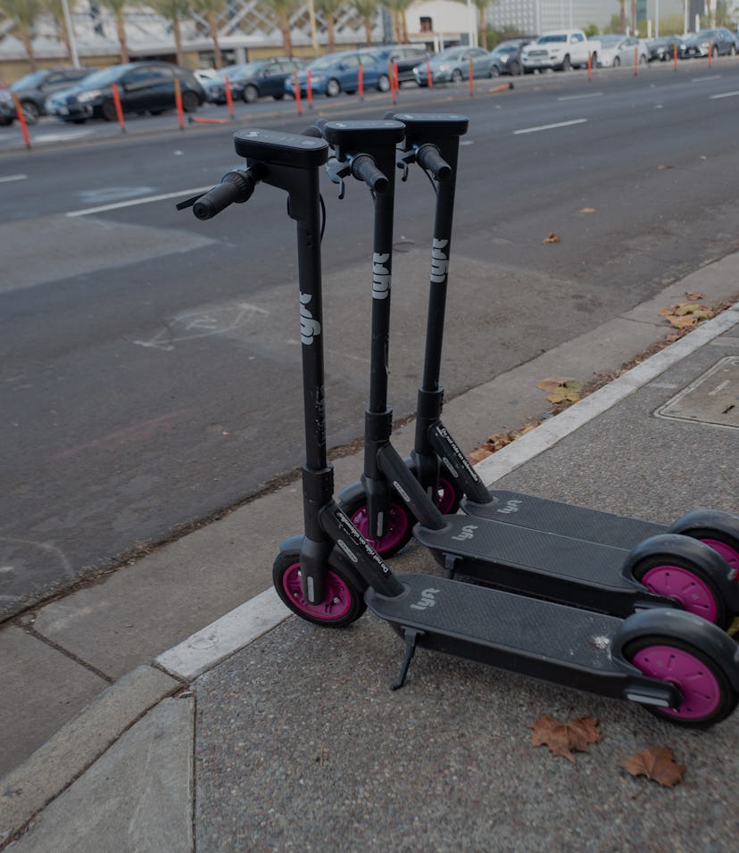 Two Lyft electric scooters parked on a sidewalk.