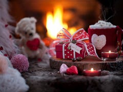 A Valentine's Day spread of hot cocoa bombs is placed next to a fireplace. 