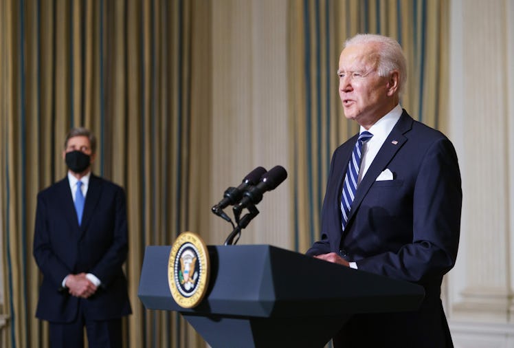 President Biden speaking at a lectern with climate envoy John Kerry in the background.