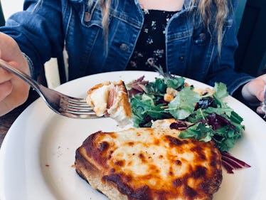 A woman enjoys a cheesy bread dish.