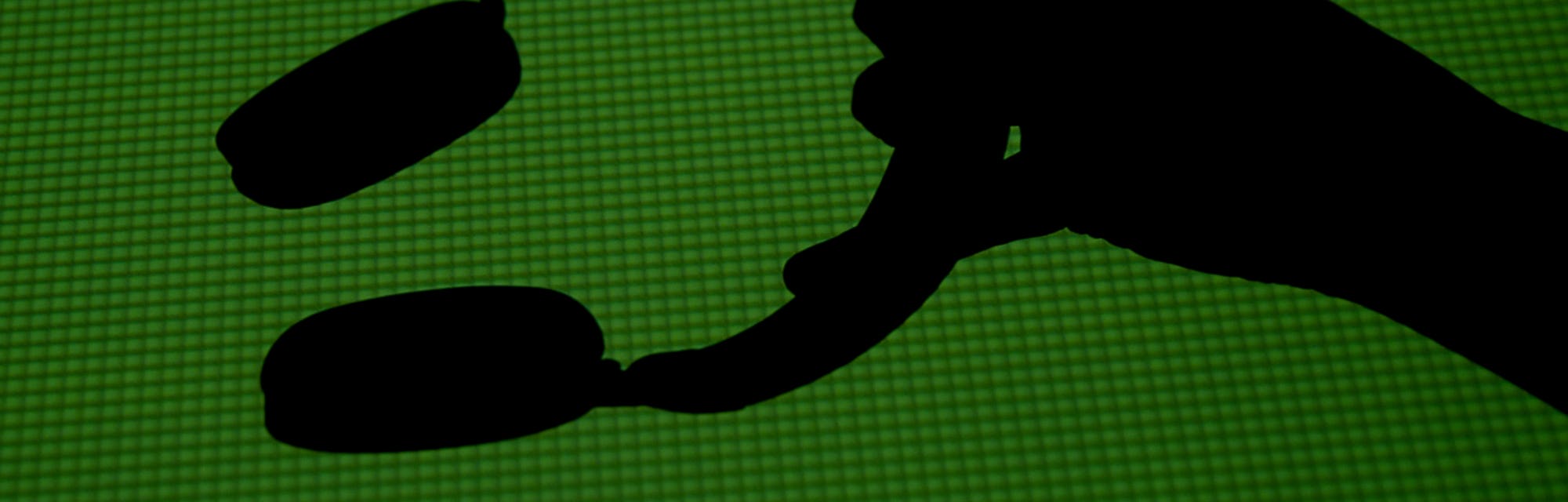Silhouette of a hand holding a pair of headphones.