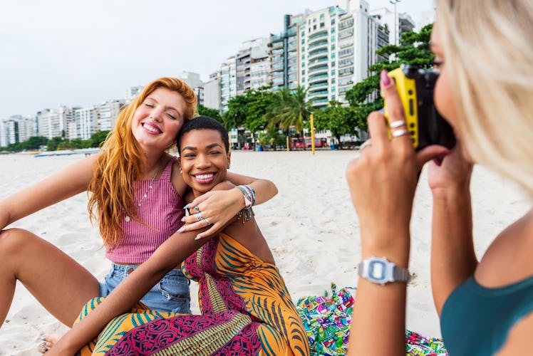Three friends enjoy the beach and pose for a picture while sitting in the sand on spring break.