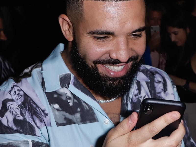 Musician Drake is seen beaming at his phone.