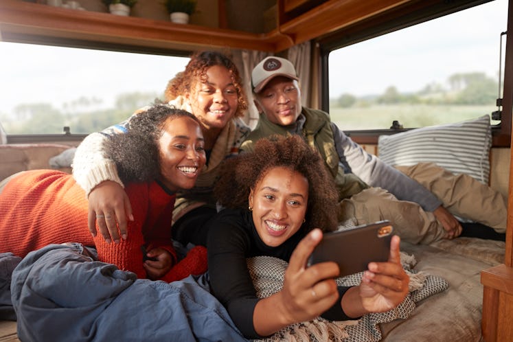 A group of friends all huddle close together for a picture together in the back of their RV. 