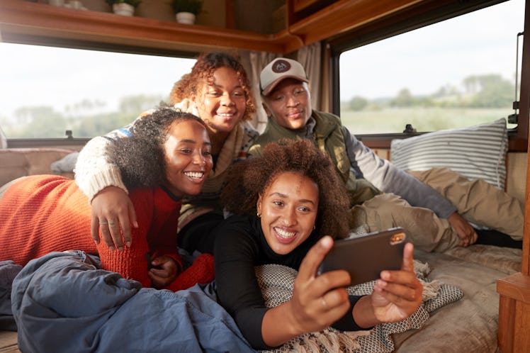 A group of friends all huddle close together for a picture together in the back of their RV.