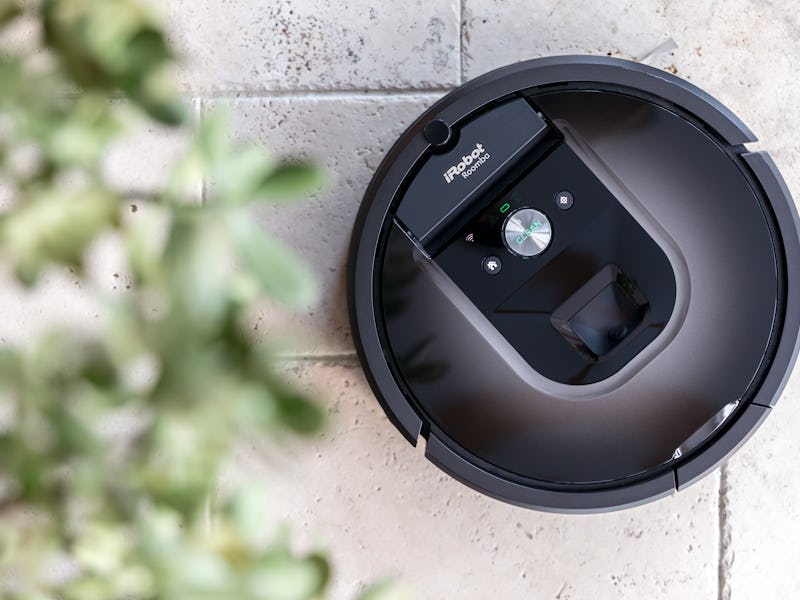 An iRobot Roomba is seen placed near a bush.