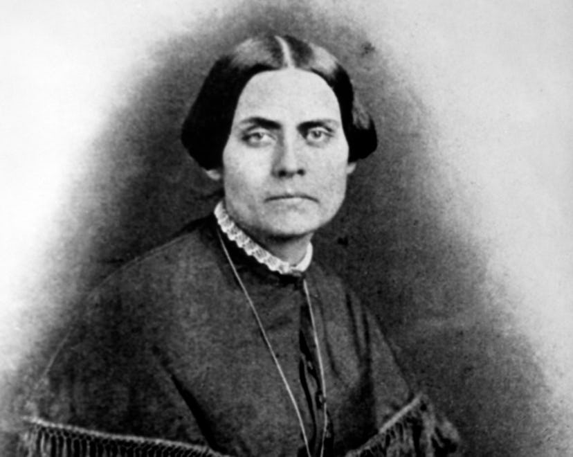 Susan B. Anthony sits in a dark dress and white collar in this black-and-white illustration.