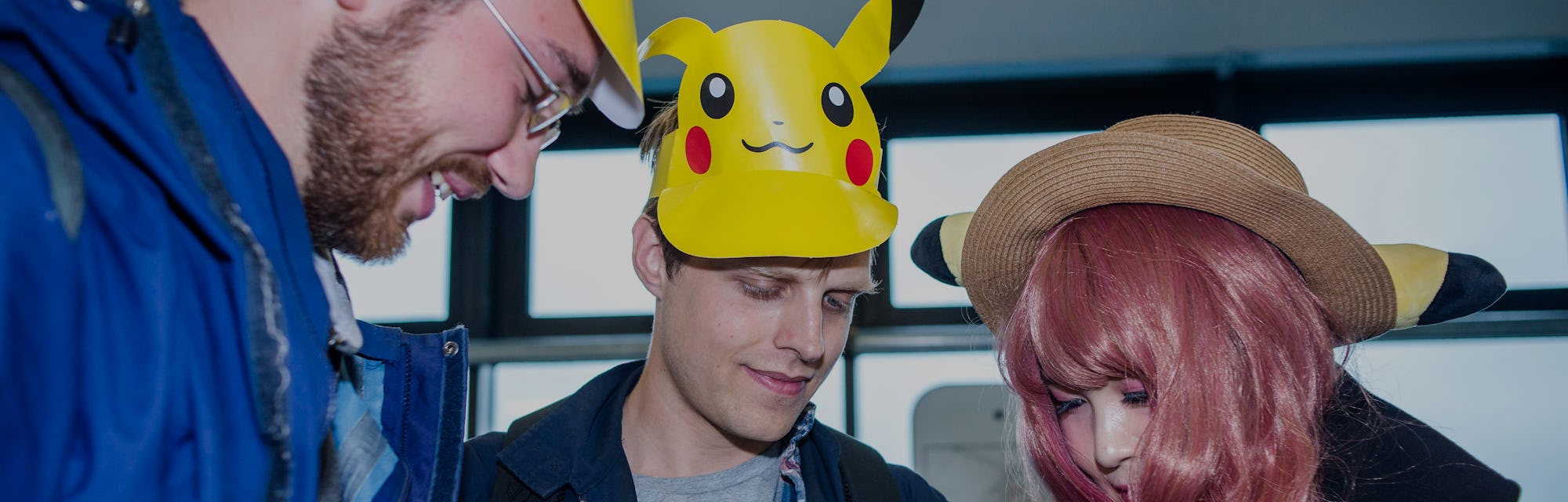 A trio of Pokemon players are seen hovering over their phones.