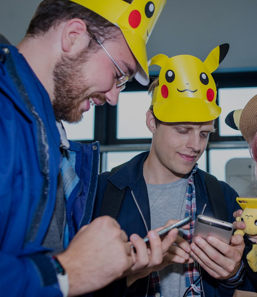 A trio of Pokemon players are seen hovering over their phones.