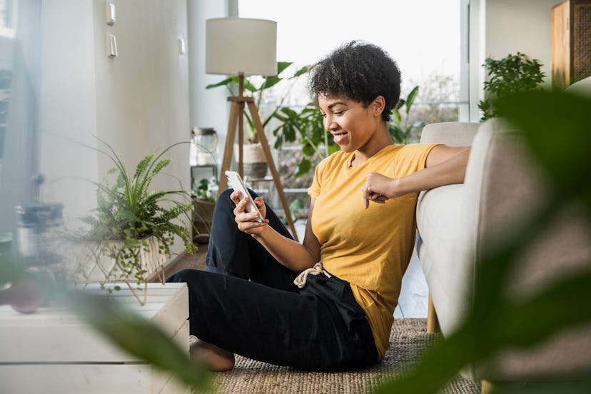 A woman looks at her phone in her living room. Twitter's Super Follows feature was announced on an i...