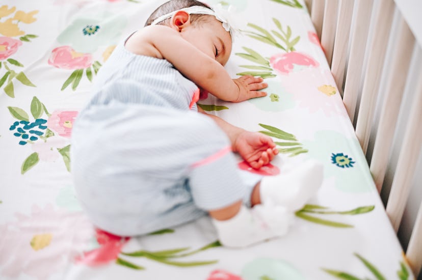 Baby sleeping on side in a crib, in a story answering the question, why do babies sleep with their b...