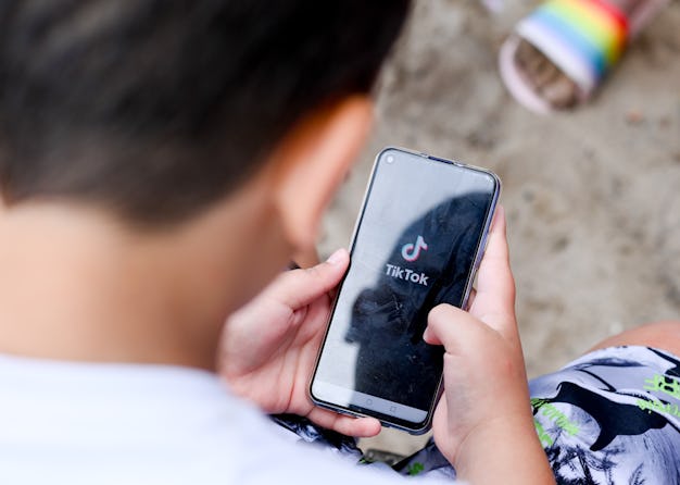 A little boy is seen using a smartphone. On the screen, it shows he is using TikTok.