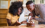 A happy couple decorates a mini cake for Super Bowl Sunday using these super bowl dessert recipes fr...