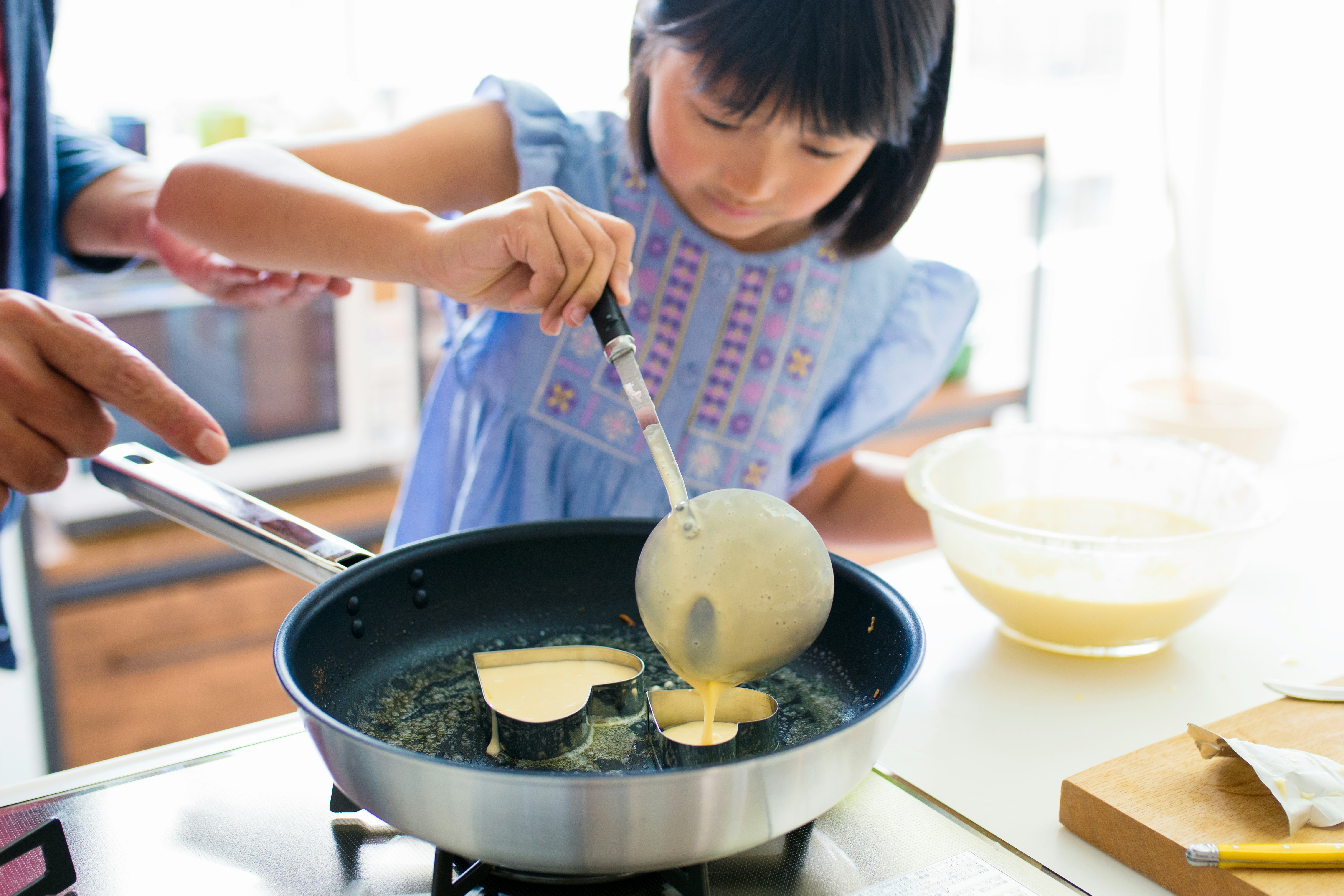 young girl making pancakes for mother's day