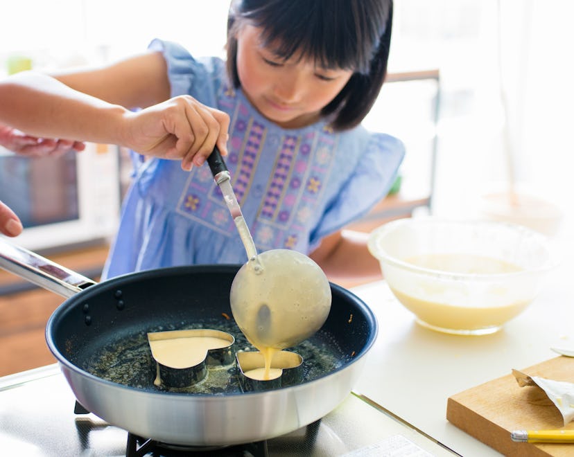 young girl making pancakes for mother's day