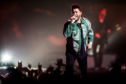 The Weeknd performs on stage in a green jacket.