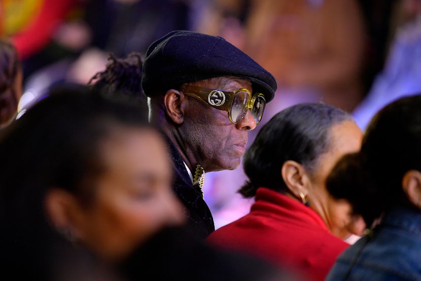Dapper Dan at an event in a crowd wearing a Gatsby cap and a pair of oversized shades