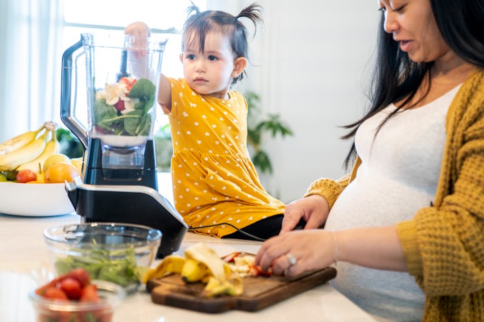 toddler girl and pregnant mom making a smoothie