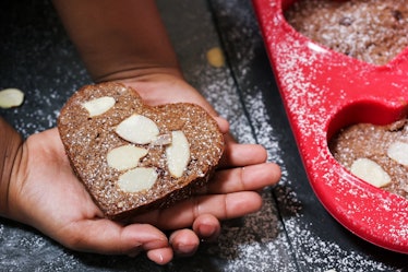 A woman holds a heart-shaped brownie. 