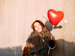 A young woman poses in the sunshine with a heart-shaped balloon for a Valentine's Day photo session.