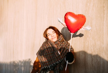 A young woman poses in the sunshine with a heart-shaped balloon for a Valentine's Day photo session.