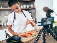 A woman cooks salmon in her kitchen. 