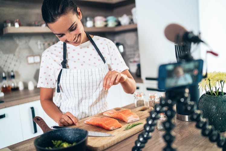 A woman cooks salmon in her kitchen.