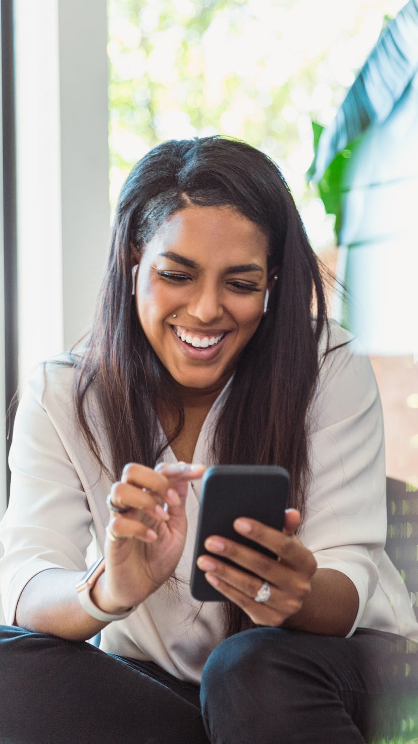 A woman looks at her phone laughing at Twitter's Super Follows feature.
