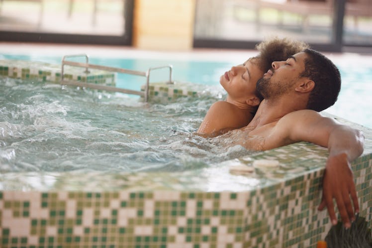 Young couple is having a relaxing bath in a hot tub. They are having a romantic weekend at wellness ...