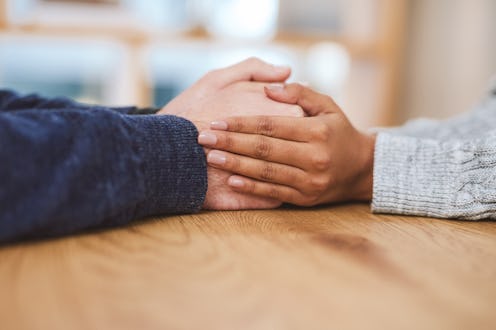 Cropped shot of an unrecognizable couple sitting together at home and holding hands