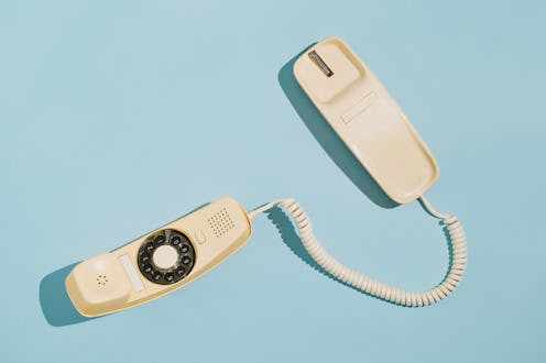 From above of a yellow rotary dial telephone off the hook on a blue background. Arkansas' latest an...