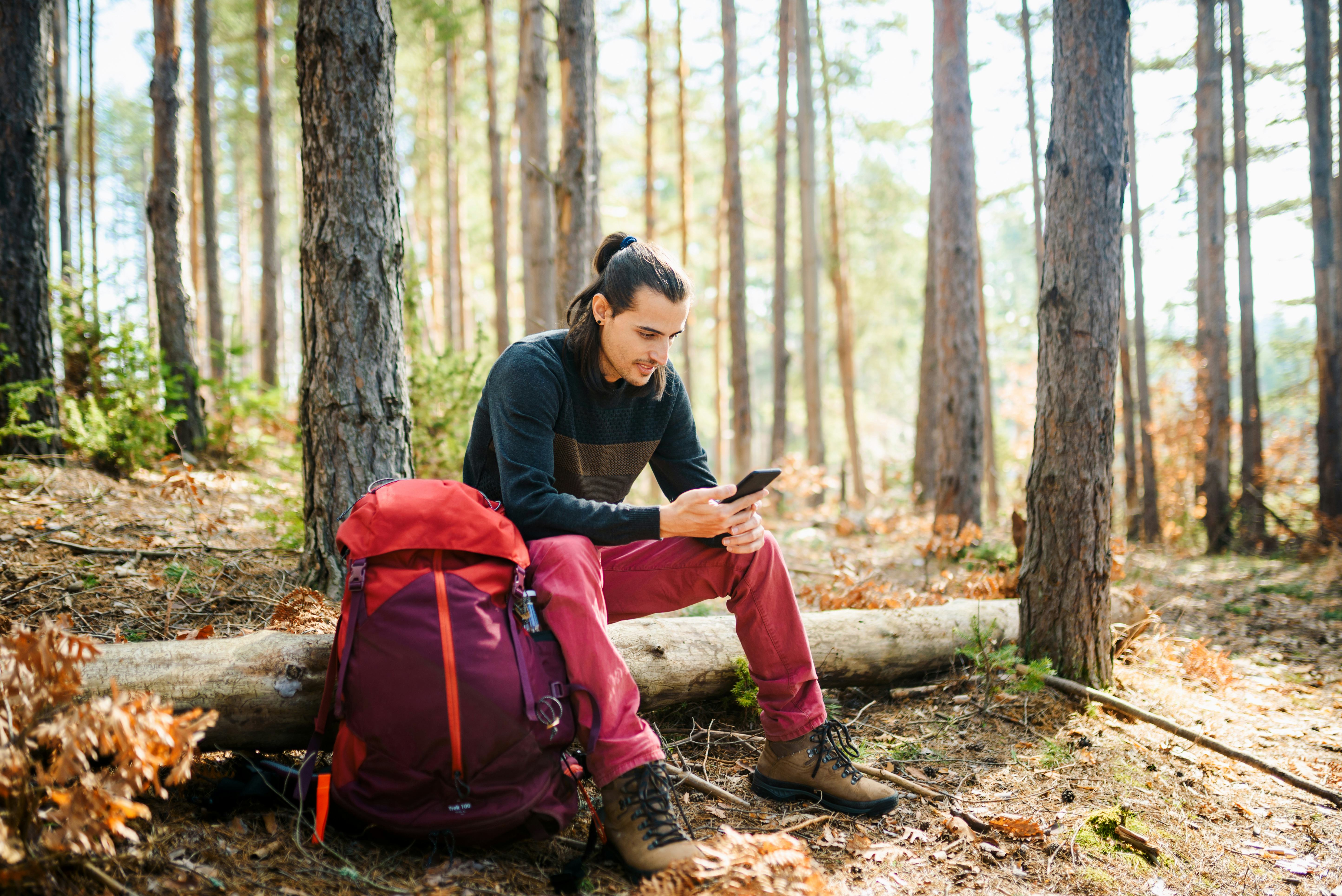 Young caucasian man using a smart phone in the nature.  Using technology in the nature concept.
